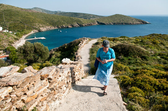Woman walking up steps from a beach on Fourni Island, Greece.