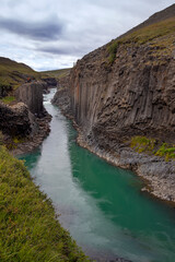 Fototapeta na wymiar Breathtaking view of Studlagil canyon in Jokuldalur Valley in Iceland. Basalt columns and turquoise glacier river.