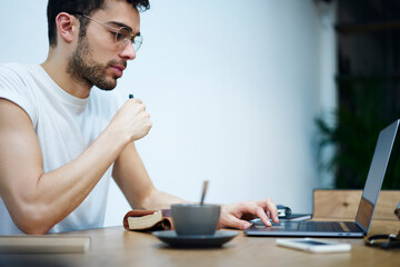 Thoughtful ethnic man browsing laptop