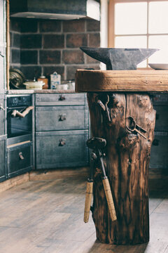 tree trunk with tools and an anvil in a luxury cast iron style kitchen
