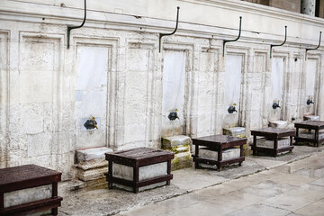 Fototapeta na wymiar view of water taps and benches against the gray wall next to the mosque. Washing hands and feet.Islam is a religion.Sulaymaniyah mosque in Istanbul in Turkey