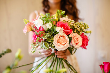 a woman florist makes a bouquet of bright pink and green flowers in a flower shop.Bouquet of pink roses, white bell,green greenery.Selective focus
