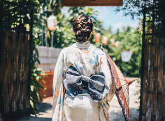 Rear view of Japanese woman wearing Yukata dress while walking in town. A Japanese yukata is a...