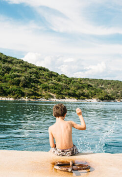 Boy throwing some pebbles into the sea