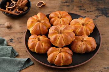 Pumpkin buns bread with spices on brown background. Halloween Food Concept. Autumn concept.