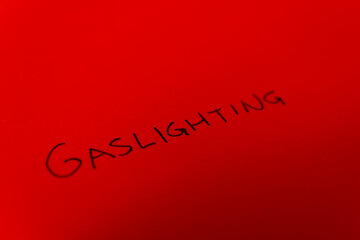 Word Gaslighting, written on a red paper with black ink
