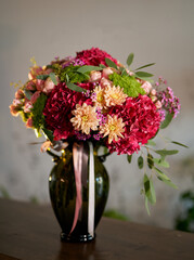 Adorable flower bouquet in dark green vase. Red hydrangeas, yellow chrysanthemums, pink roses as fresh flowers business concept.