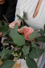 Girl holding a bridal bouquet. Eucalyptus leaves. Roses. Close-up
