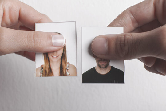 Couple holding their passport photo and hiding their eyes.