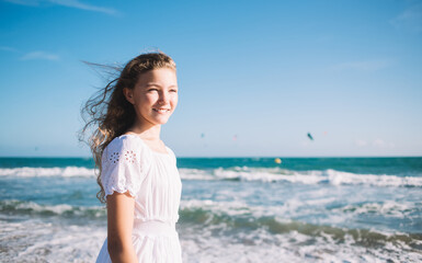 Fototapeta na wymiar Cheerful girl walking on beach near waving sea