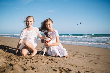 Cheerful girls with dog resting on beach