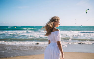 Fototapeta na wymiar Little schoolgirl standing near waving sea in sunny day