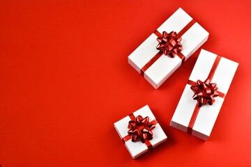 White gifts boxes with a red ribbon on a red background. Postcard for Valentine's Day or Mother's Day, Christmas and New year. copy space, flat lay. Holiday concept.
