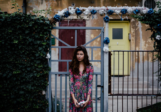 Beautiful girl in floral print dress in front of old Balkan home