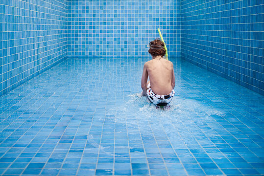 Boy having fun on a skateboard as a blue tiled swimming pool is filling with water