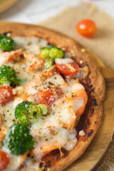 Cheesy Keto Pizza with Tomatoes Broccoli And Salmon for ketogenic diet. set on white cafe table.