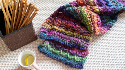 hand knit scarf with a box of knitting needles 
