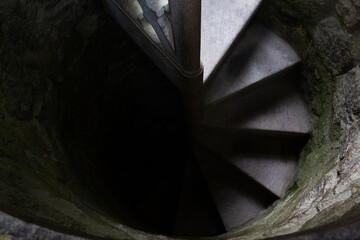 Top view of spiral stone staircase leading from light into darkness. Going towards the unknown, fear, afraid concepts