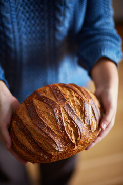 Woman's hands holding large loaf of bread
