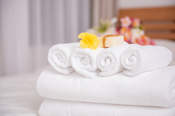 Fototapeta na wymiar White towels,soap,candle and beautiful frangipani or plumeria flowers in bamboo wooden basket on modern white bedroom