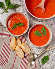 Overhead view of two bowls of vegan roasted tomato basil soup with bread