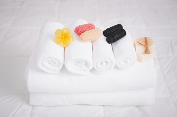 Fototapeta na wymiar Spa object with white towels,organic soap,luffa scrub, and plumerai flower candle on clean white bedding.