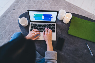 Crop woman working on project on laptop at home