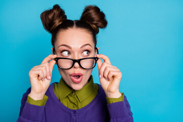 Closeup photo of attractive lady two funny buns good mood take off vision eyesight specs interested look side empty space wear shirt collar violet sweater isolated blue color background