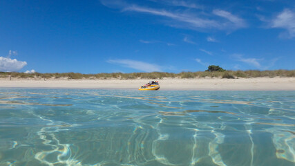 A paddle surf board in the shore of a beach in the mediterranean sea with turquoise water and blue sky. Summer fun activity.