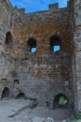 inside old ancient stone tower with small windows of Genoese fortress in Feodosia made of sand brown colored bricks. Crimea, summer. Blue sky with clouds backdrop. Historic place