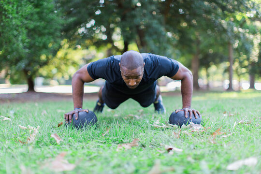 African-American man doing push-ups on slam balls