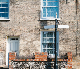 A village house with a flit wall and a signpost outside.