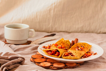 Gluten-free keto Crepes filled with pear, walnut and cinnamon in the oven with sea buckthorns on top. Autumn vegetarian breakfast or healthy dessert concept