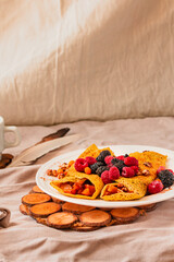 Gluten-free crepes stuffed with roasted pear, walnut and cinnamon, in the oven with fresh berries on top. Autumn comfort breakfast served on a natural linen background. Selective focus. Free space for