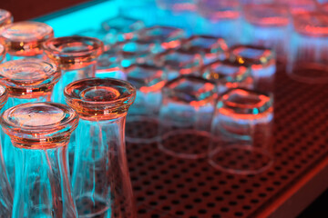 close up empty drinking glasses putting upside down inside bar counter at night. 