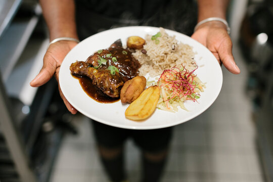 Cook with Plate of Fry Plantain and Jerk Chicken