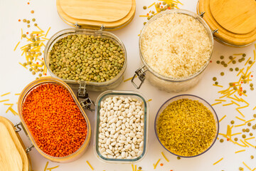 Uncooked dry cereal food group in glass containers on white,above view