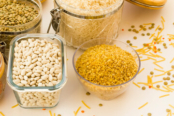Uncooked dry cereal food group in glass containers on white,above view