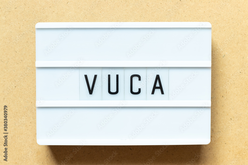 Wall mural Lightbox with word VUCA (abbreviation of Volatility, uncertainty, complexity and ambiguity) on wood background