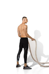 Ropes. Stylish young male athlete practicing on white studio background, portrait with shadows. Sportive fit model in works out in motion and action. Body building, healthy lifestyle, style concept.