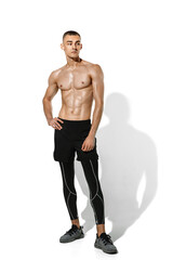 Fototapeta premium Posing. Stylish young male athlete practicing on white studio background, portrait with shadows. Sportive fit model in works out in motion and action. Body building, healthy lifestyle, style concept.
