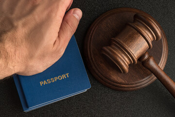 Male hand holds passport next to wooden gavel. Obtain citizenship. Legal immigration.