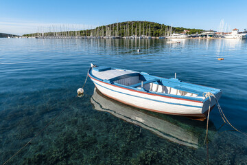 Wooden fishing boat and its reflection in the clear water in the bay in the Adriatic sea in Rogoznica, Croatia