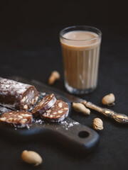 Chocolate salami sausage on a dark background. Homemade dessert made from cookies, butter, cocoa and milk.