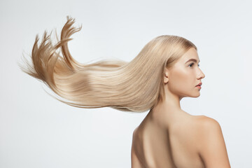 Beautiful model with long smooth, flying blonde hair isolated on white studio background. Young...