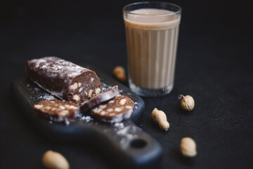 Chocolate salami sausage on a dark background. Homemade dessert made from cookies, butter, cocoa and milk.