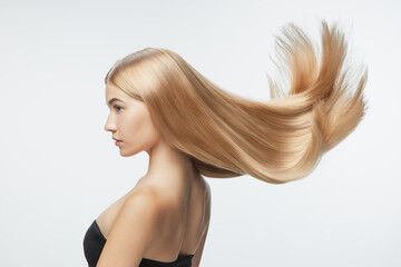 Beautiful model with long smooth, flying blonde hair isolated on white studio background. Young...