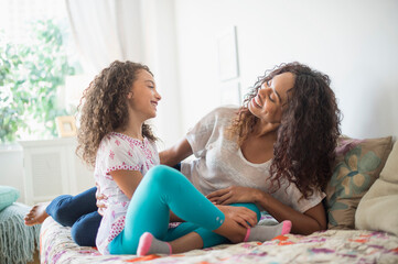 Mother and daughter (8-9) sitting on bed