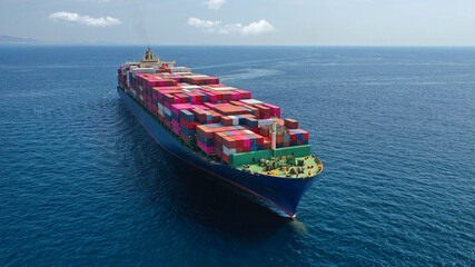 Aerial drone photo of huge container cargo Ship carrying load in truck-size colourful containers...