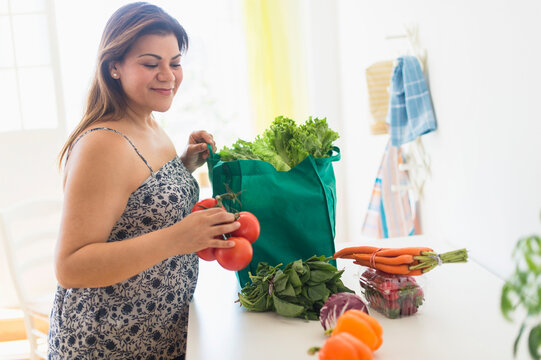Woman taking out vegetables of grocery bag